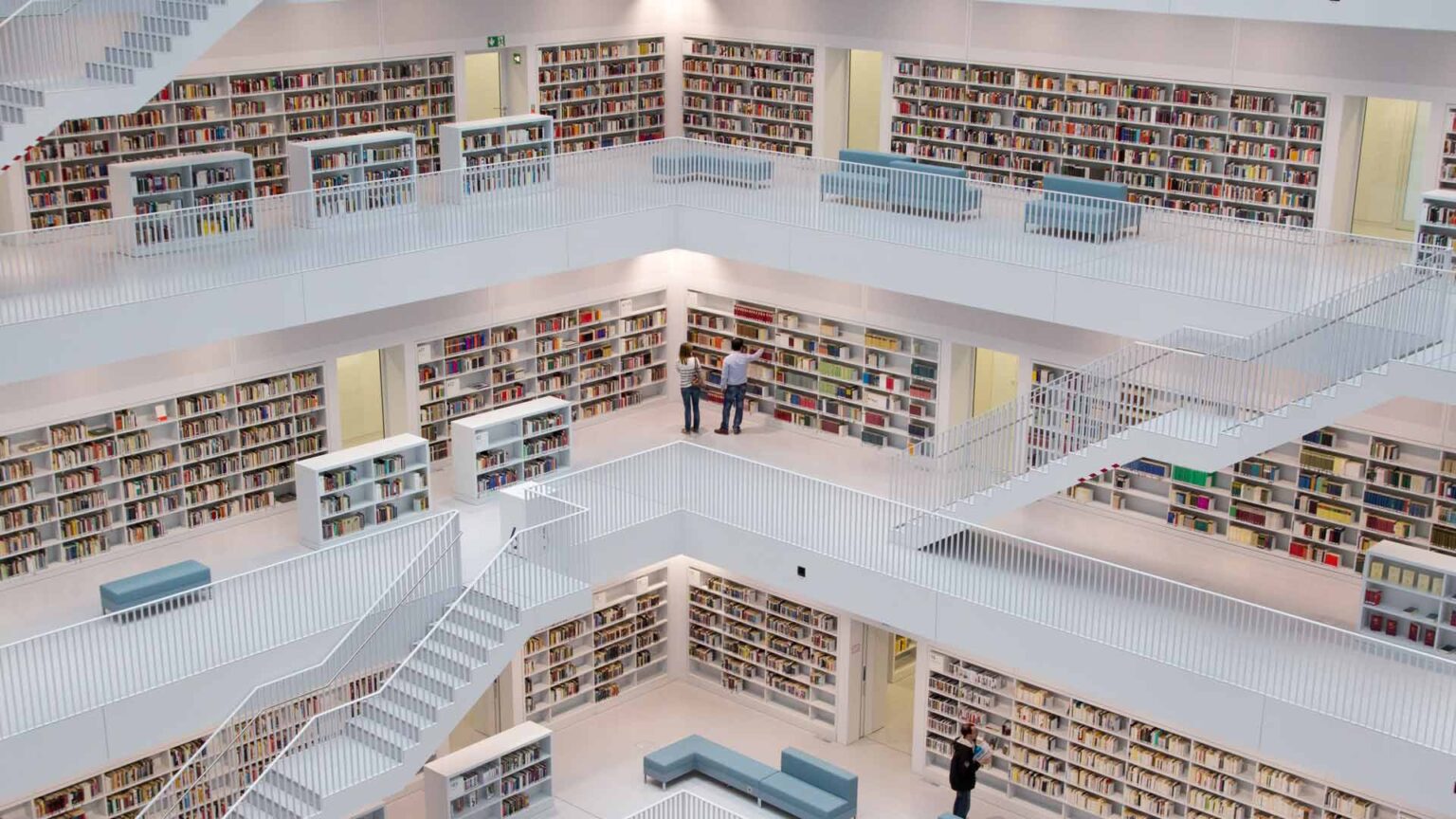 Una biblioteca moderna con pisos blancos pulidos y sofás seccionales minimalistas para mejorar la actividad cognitiva.
