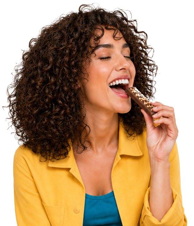 Woman smiling and enjoying a chocolate snack bar.